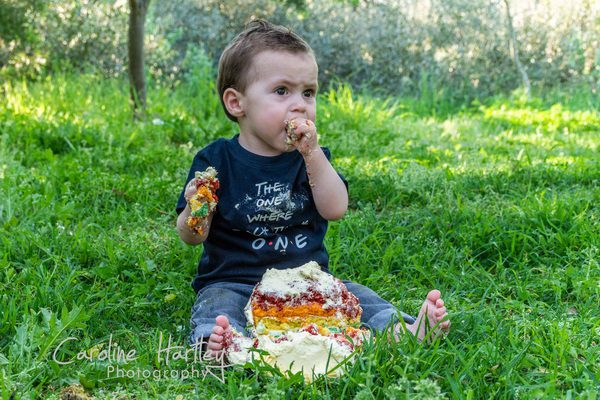 Child sitting in field eating birthday cake 