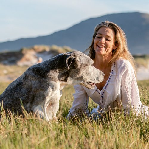 Woman sitting with a dog in the field